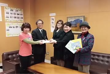 5人の男女が図書券や書面を持って立っている写真