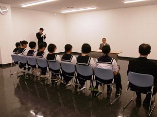 教育長と机を挟んで、8人の制服を着たソフトテニス部の女子生徒と1人の男性が椅子に座っている写真