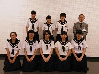 前列に5人、後列に3人のソフトテニス部の女子生徒とその隣に並んだ教育長の笑顔の記念写真