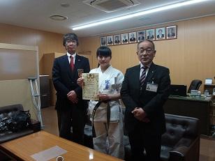 右から教育長、賞状を持った道着姿の女子生徒、男性の3人を正面から撮った写真