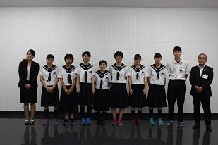 6人の制服を着た女子生徒と1人の男子生徒が並び、その右にスーツを着た男性と、左にスーツを着た女性が立って並んでいる写真