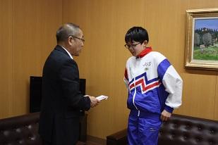 スーツを着た男性が、ユニフォームを着た男子生徒に賞状を渡している写真