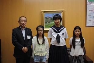 右から、白い服を着た女子生徒、制服を着た女子生徒、白い服を着た女子生徒、スーツを着た男性が並んで立っている写真