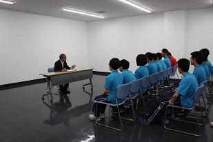 椅子に座り教育長の話を聞く水泳全国大会出場の生徒たちの写真