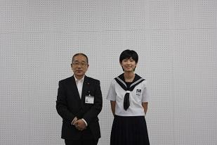 白い背景で教育長と記念撮影する女子生徒の様子
