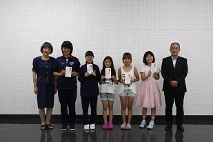 右からスーツを着た男性と、5人の女子生徒と、女性が並んでいる写真