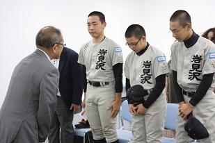 スーツを着た男性と、3人ユニフォームを着た男子生徒が向かい合っている写真