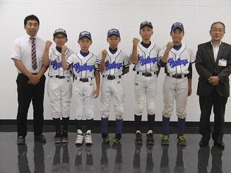 右から、スーツを着た男性と、5人のユニフォームを着た男子生徒と、白いシャツにネクタイをした男性の写真