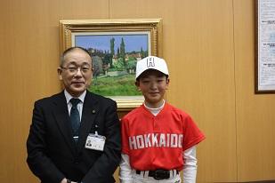 白いキャップをかぶりオレンジ色のユニフォームで教育長と並ぶ男子小学生の写真