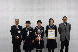 賞状を乗って立つ女子中学生3人と教育長の写真