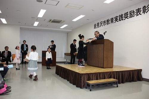 研修室で体育、文化活動で活躍した児童生徒を表彰する教育長の写真