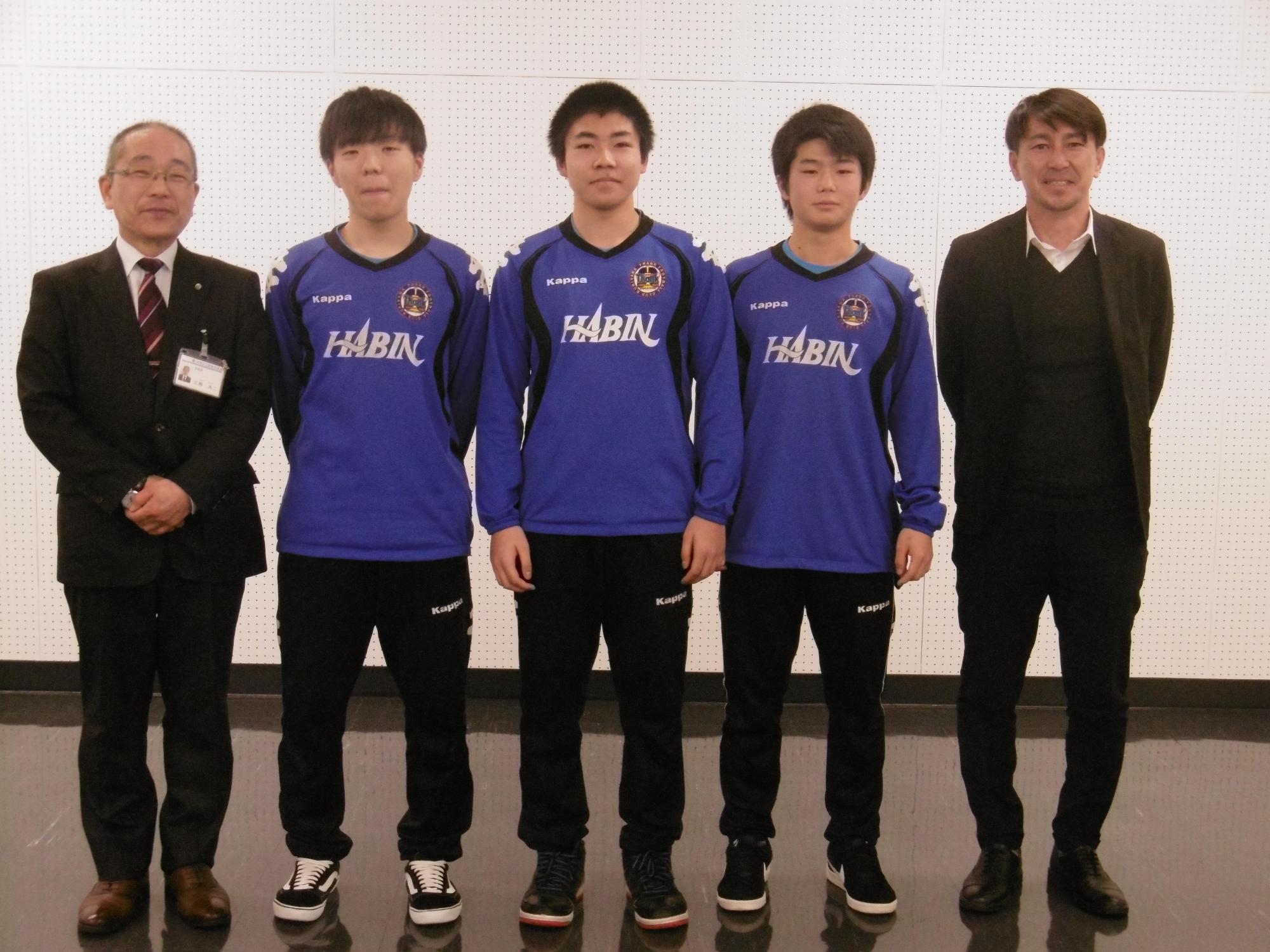 フットサル全国大会に出場した学生と教育長とスーツの男性が横一列に並んだ写真