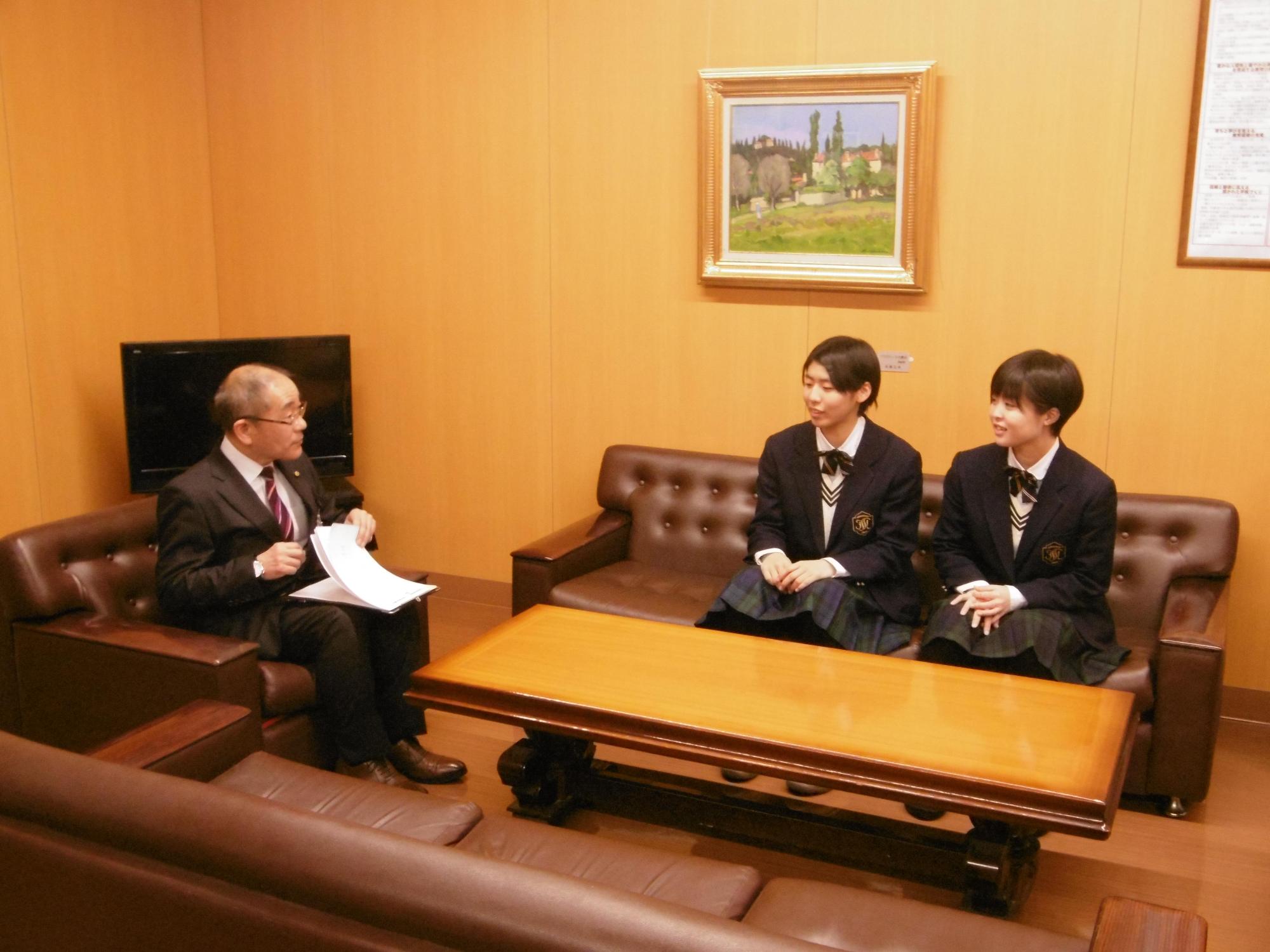 バドミントン全国大会に出場する学生と教育長がL字に座る写真