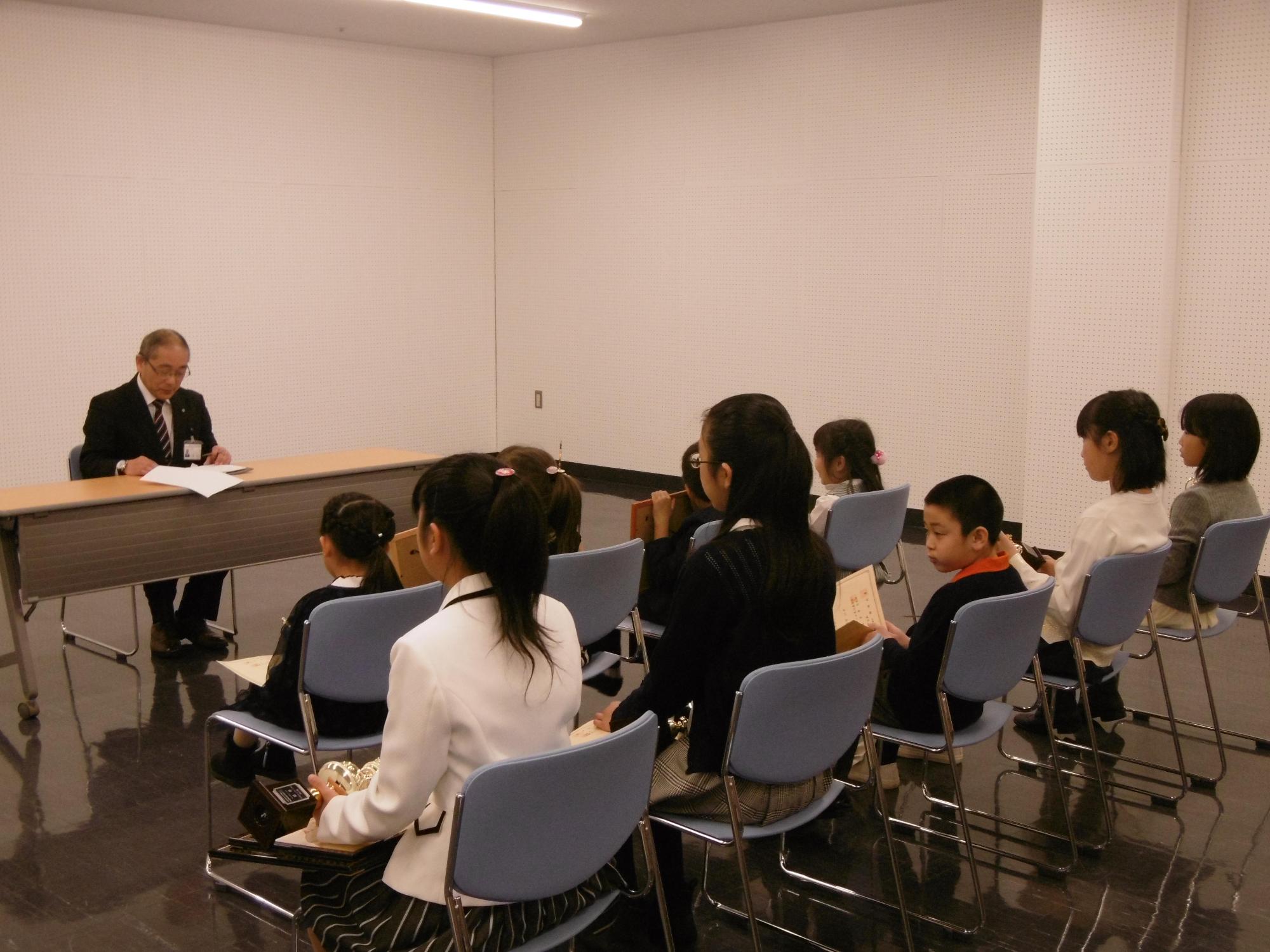 日本バッハコンクールに出場した子どもたちと教育長が対面して座る写真