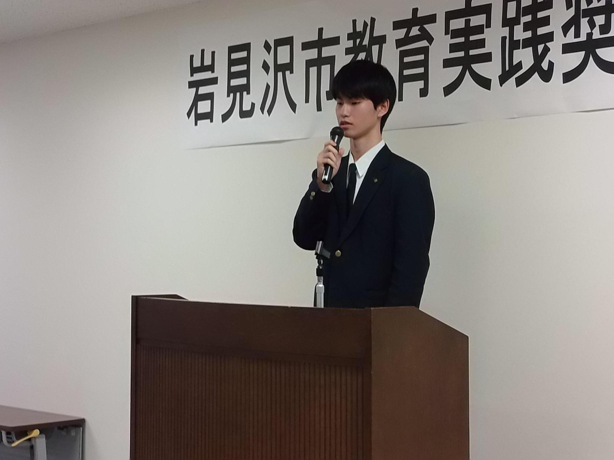 受賞者代表が壇上で挨拶をしている写真
