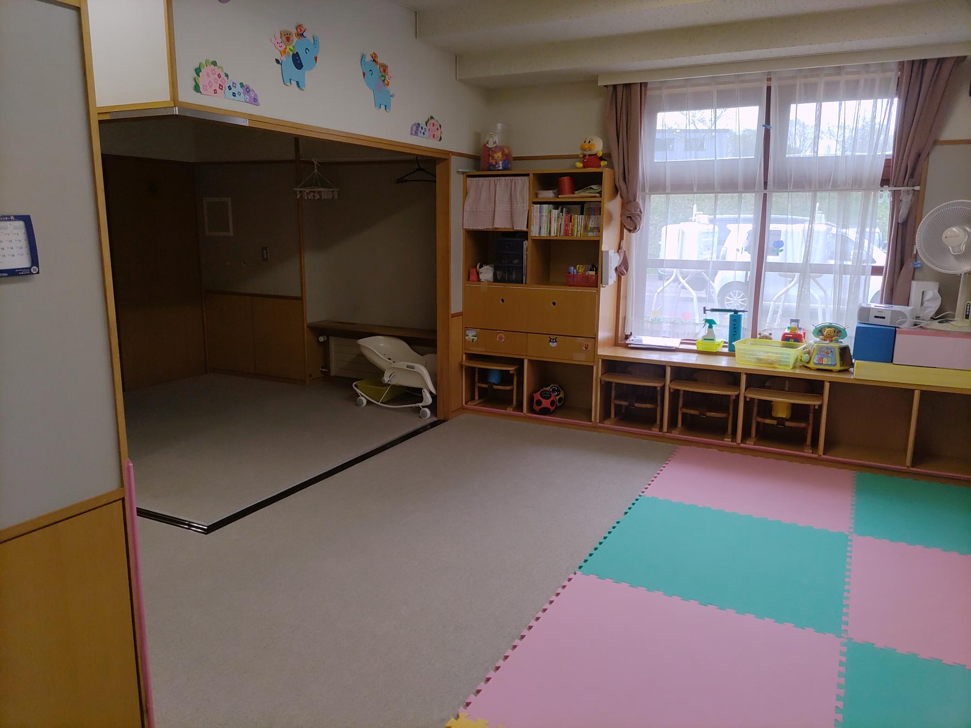 白いカーペットの上に色とりどりのマットが敷いてあり、奥にお座敷のような空間がある未満児（0歳児）保育室その3