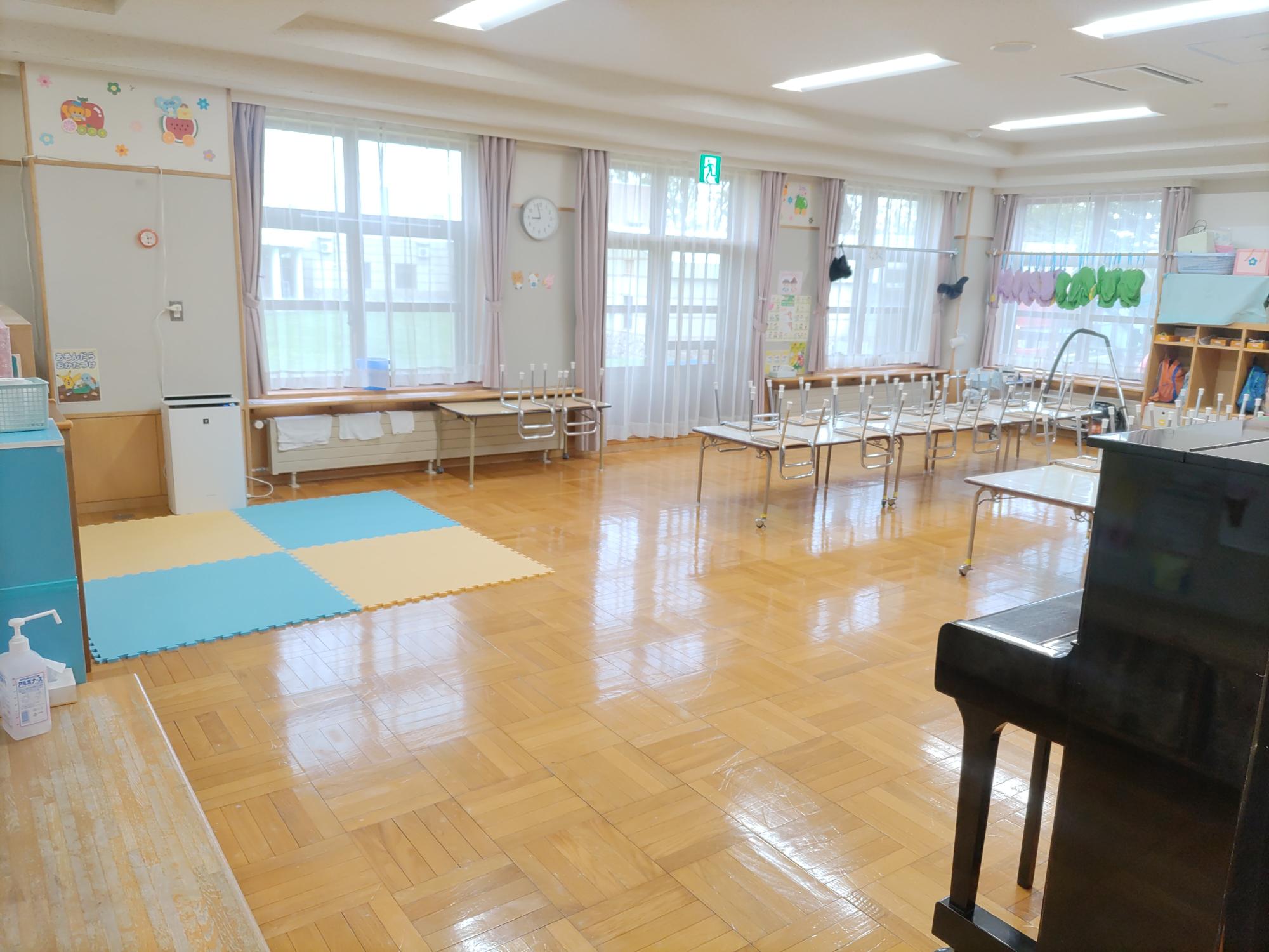 フローリングの床に白の壁、手前にピアノがある、年中、年長児（4、5歳児）保育室
