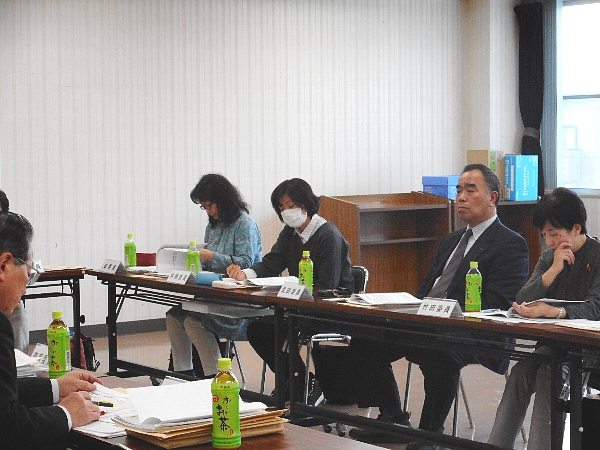 四角形に並べられた机の前の椅子に座りながら会議に参加する人々の写真