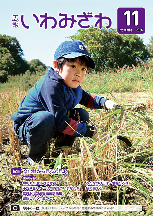 2026年9月25日（金曜日）に行われたメープル小学校と岩見沢小学校の合同稲刈りで、稲を刈る小学生の写真の広報いわみざわ2026年11月号表紙