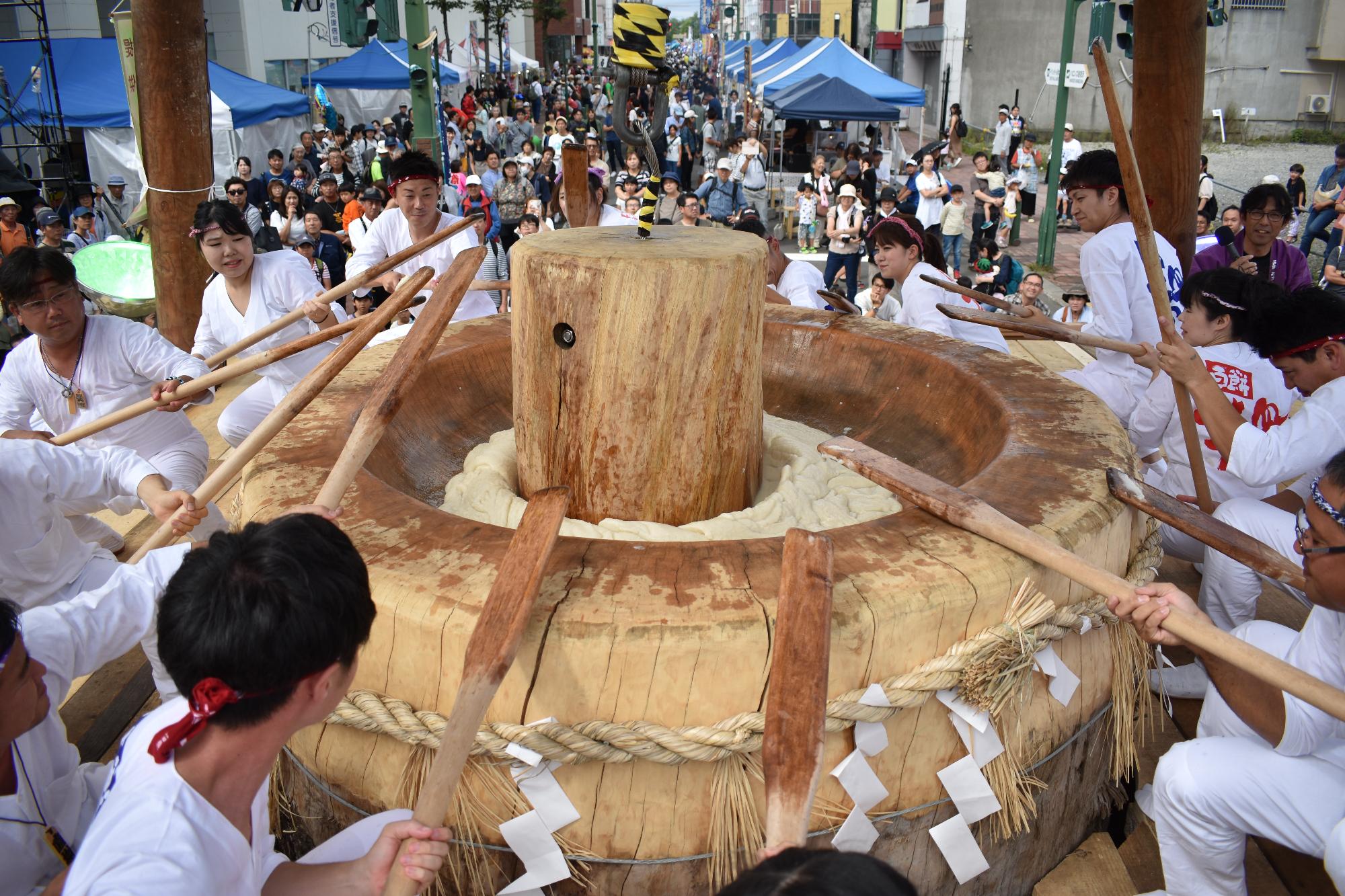 大きな臼と杵でお餅をつく様子が写ったいわみざわ百餅まつりの写真