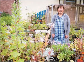 いろいろな草花の咲くガーデンに立っている川又千雪さんの写真