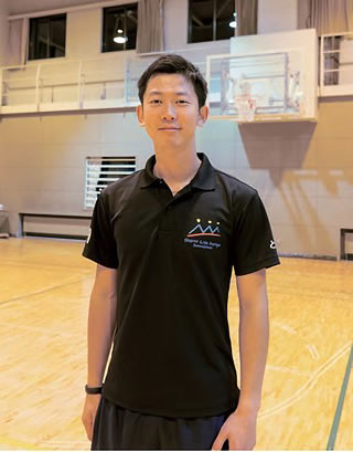 体育館のフロアに立っている辻本智也さんの写真
