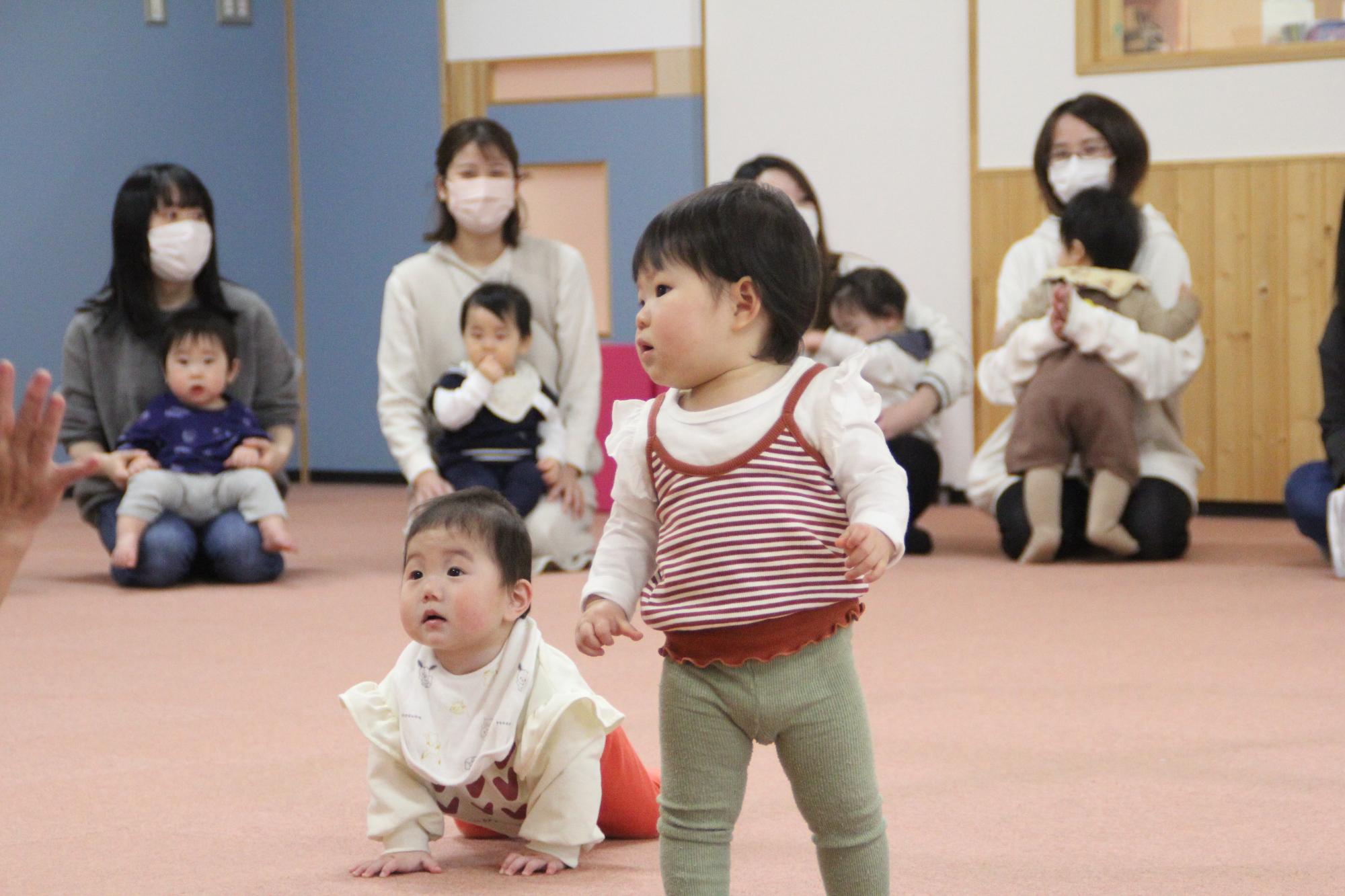 こどもを抱えたお母さんたちと元気に遊んでいるこどもたちの写真
