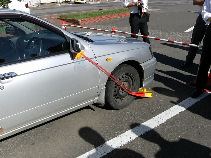 車を動かすことができないように、器具を使いタイヤをロックしている写真