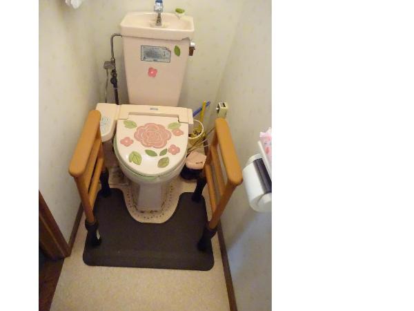 花柄の洋式トイレの両側に木製の手すりが設置されている写真