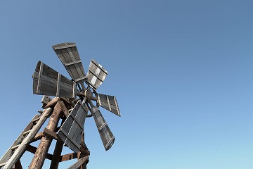 青空を背景に左側に木造の風車が写っている写真