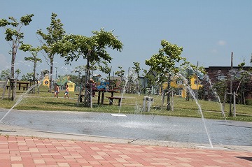 公園の水遊びができる池で噴水が上がっている写真