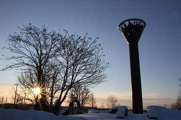 右側に塔、左側に木々と夕日が写っている写真