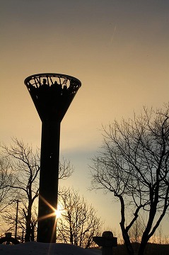 左側に塔と朝日、背景に空が写っている写真