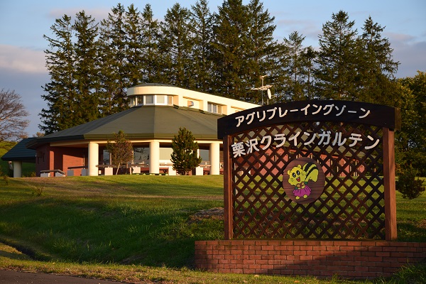 栗沢クラインガルテンの入口にある看板と奥に管理棟である「土里夢館」が写る写真