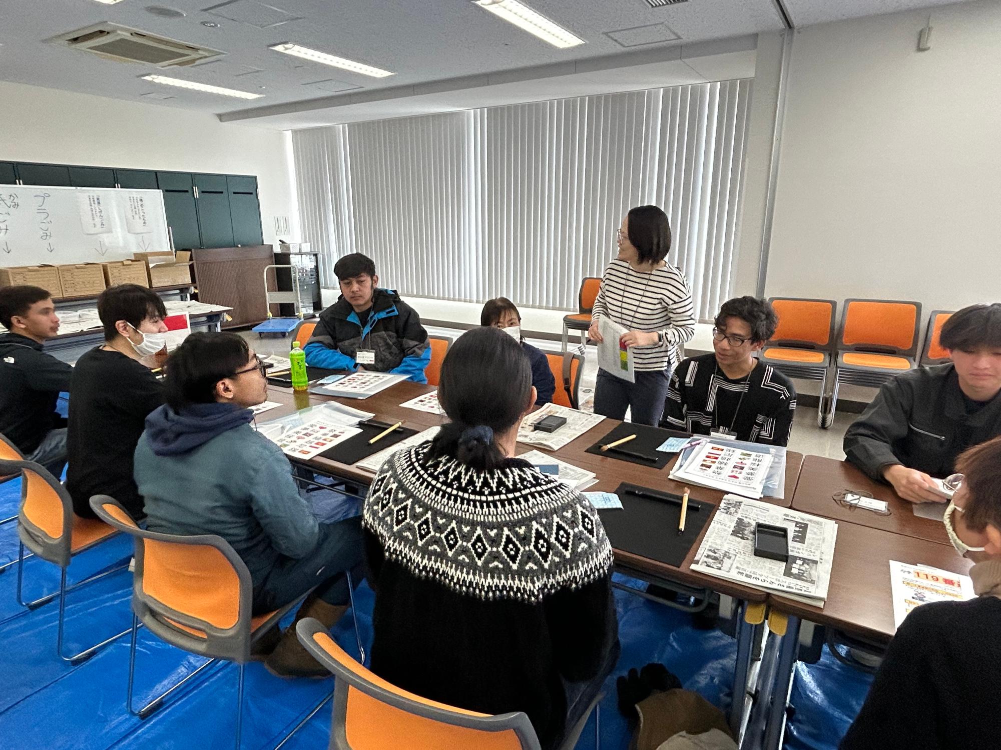 外国人の方と日本人のボランティアの方が書道で書く漢字を選んでいる様子