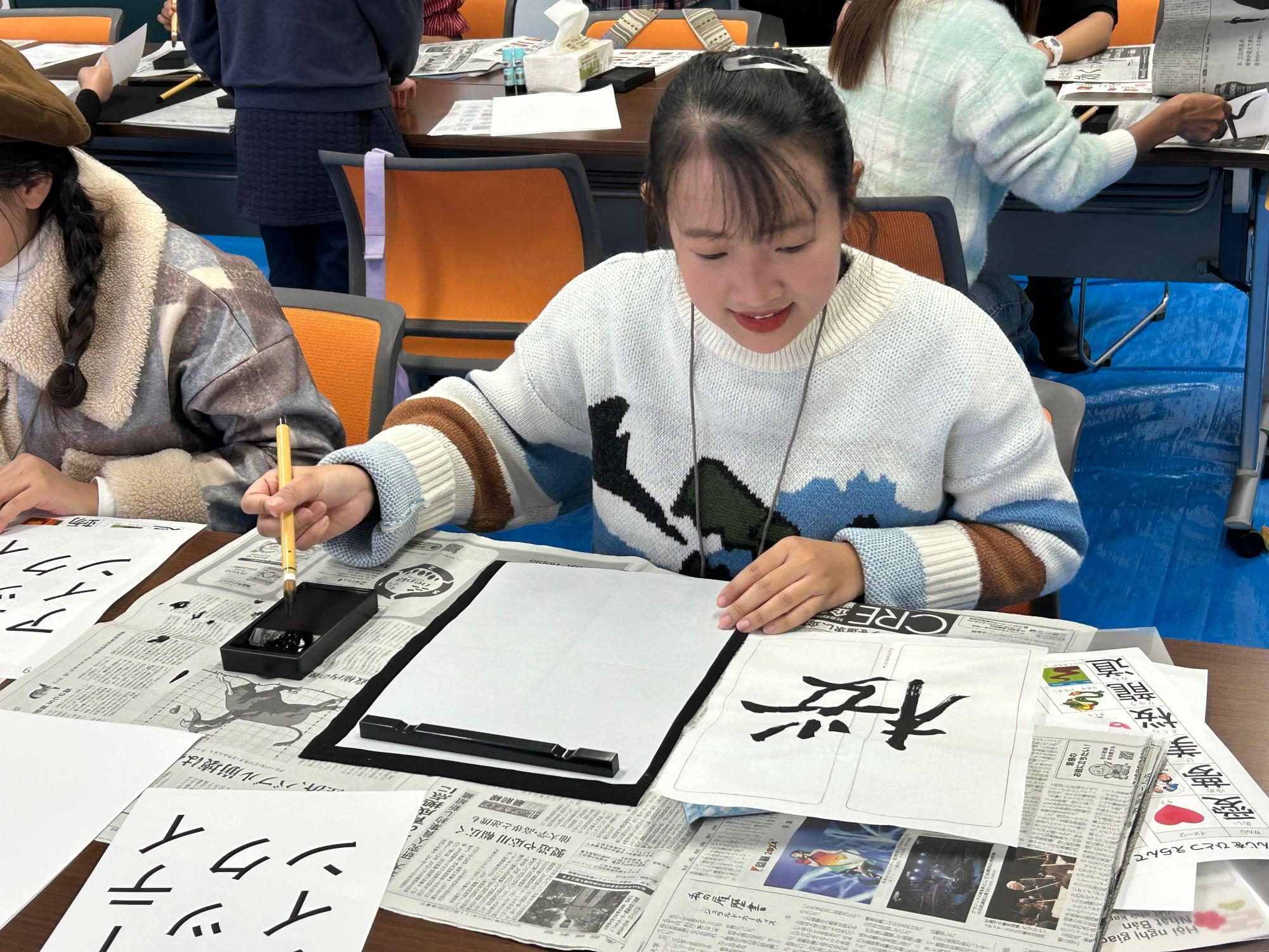 先生のお手本を見ながら書道体験をする外国人