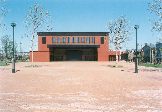 レンガは敷き詰められた広場の奥にレンガ造りのイベントホールの外観が写る写真