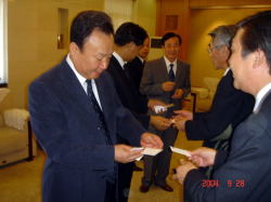 空知支庁長とともに瀋陽市農業担当副市長を表敬訪問した岩見沢市長が名刺交換をしている写真