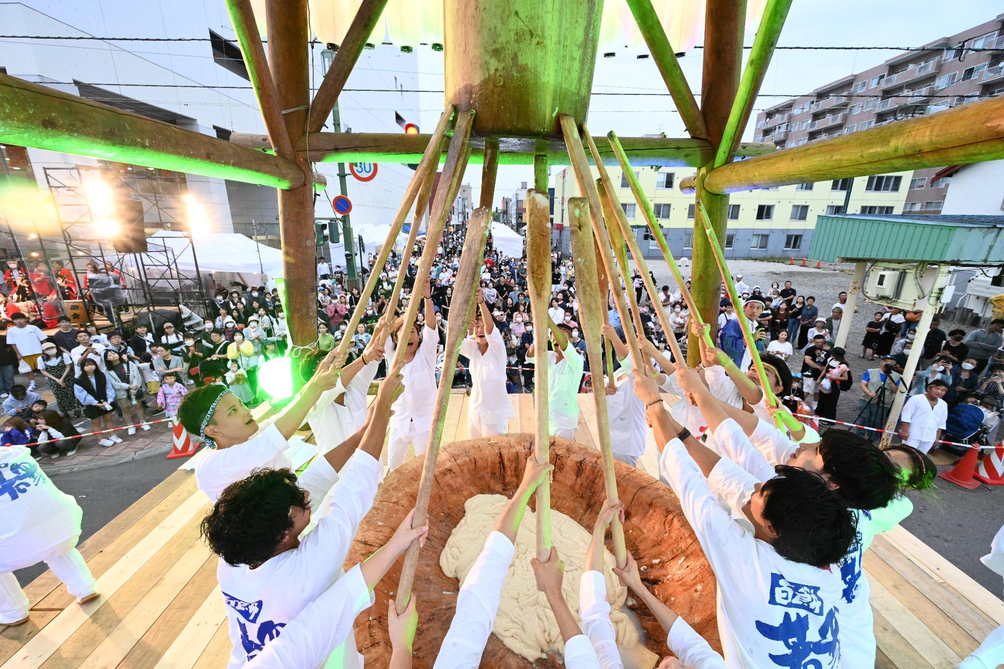 大臼餅つき中の百餅若衆とそれを見守る来場者