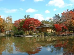 池の水面に建物と紅葉した木々が写る玉泉館跡地公園の写真