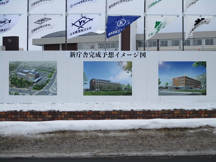 新庁舎の完成イメージを表した3枚の画像を掲載した看板を撮影した写真。