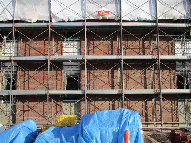 赤レンガの外壁に工事の足場が設けられている様子を正面から写した写真。