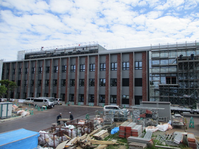 新庁舎の外観を撮影した写真。建物の手前には工事現場が、建物の右側には工事の足場が見える。