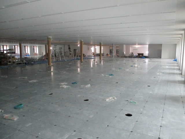 グレーの床に丸い柱がいくつか立っている広い空間の写真