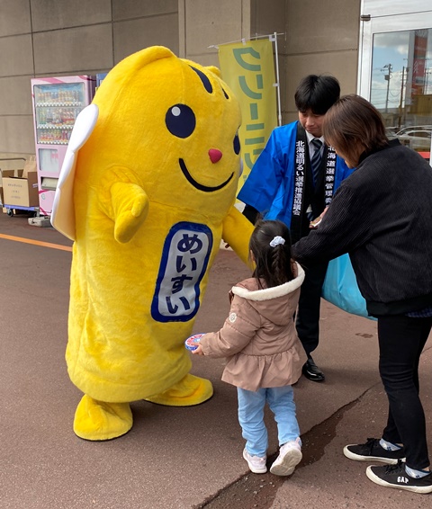 選挙のキャラクターめいすいくんと握手をしている子どもの様子の写真