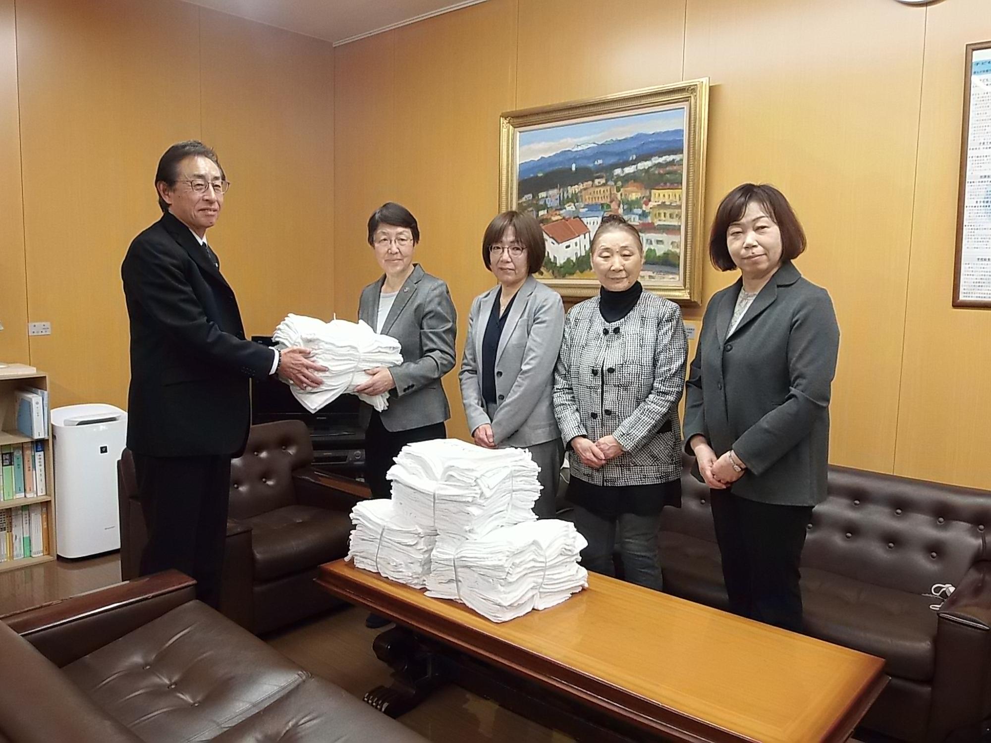 教育長室で岩見沢更生保護会女性会の4人から寄贈される白い学校用雑巾を受け取る教育長の写真