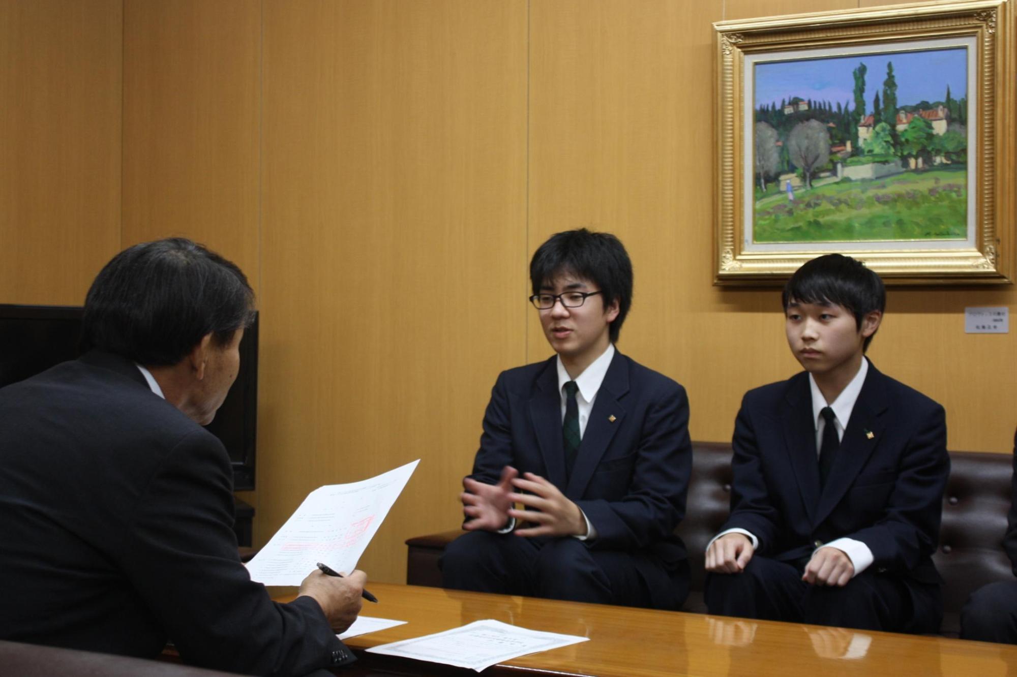 机を挟み教育長と会話する伊藤さんと岩本さんの様子の写真