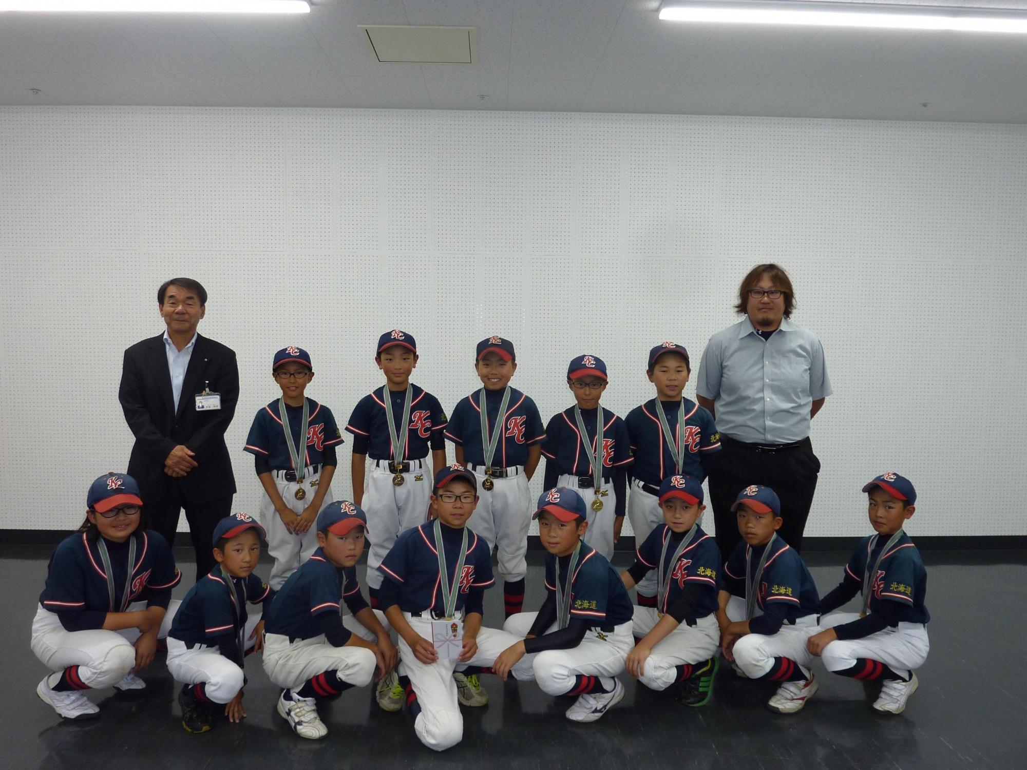 教育長と紺色に赤いラインのユニフォームが特徴的な栗沢コンバットのみなさんの写真