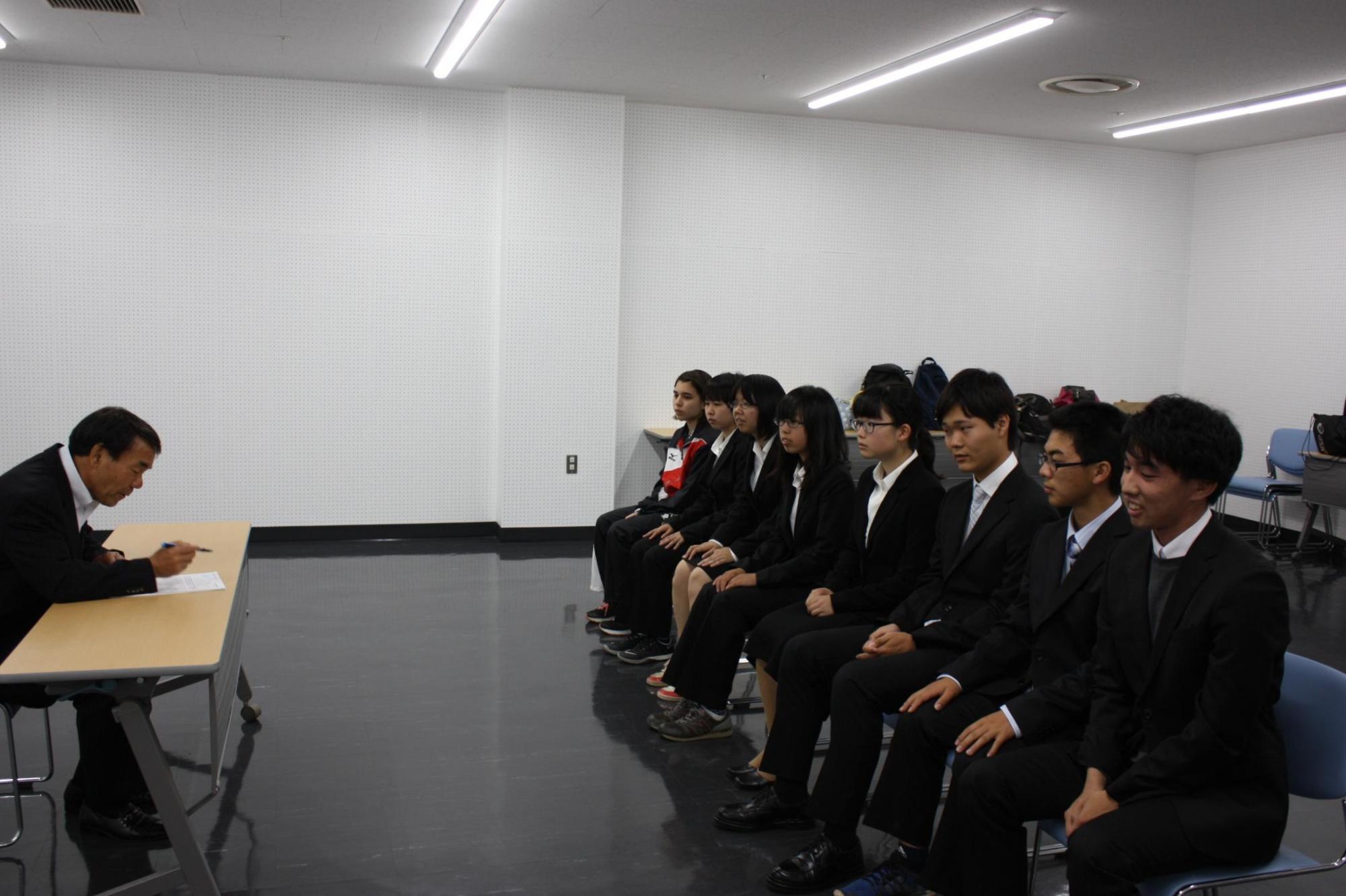 教育長と向かい合い1列に座って話を聞く生徒の皆さんの写真