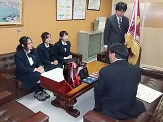 椅子に座り教育長の話を聞く簿記部の生徒達の写真
